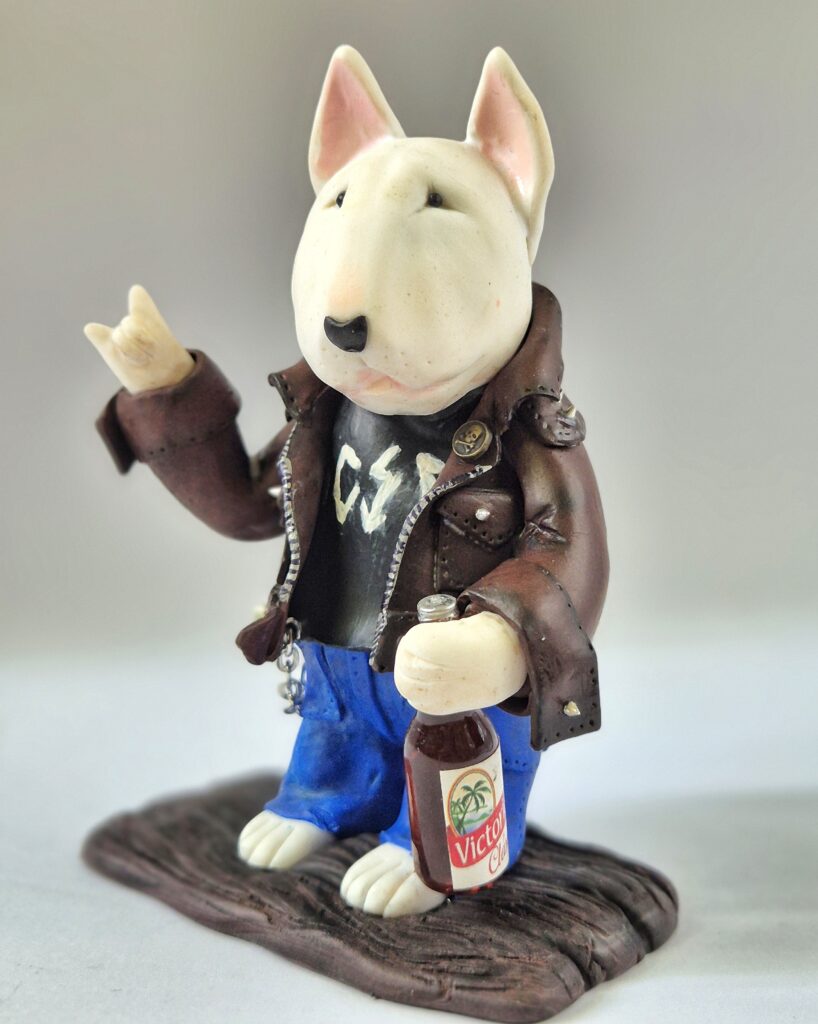 Handmade rocker Bull Terrier figurine wearing a leather jacket, blue jeans, and holding a bottle.