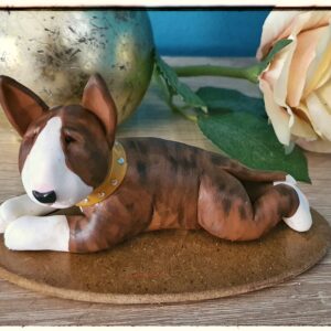 Handmade brindle Bull Terrier figurine lying down on a decorative base