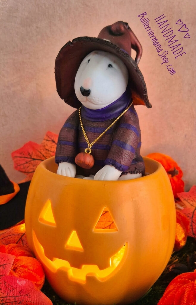 Handmade Bull Terrier Halloween figurine sitting inside a glowing jack-o'-lantern pumpkin